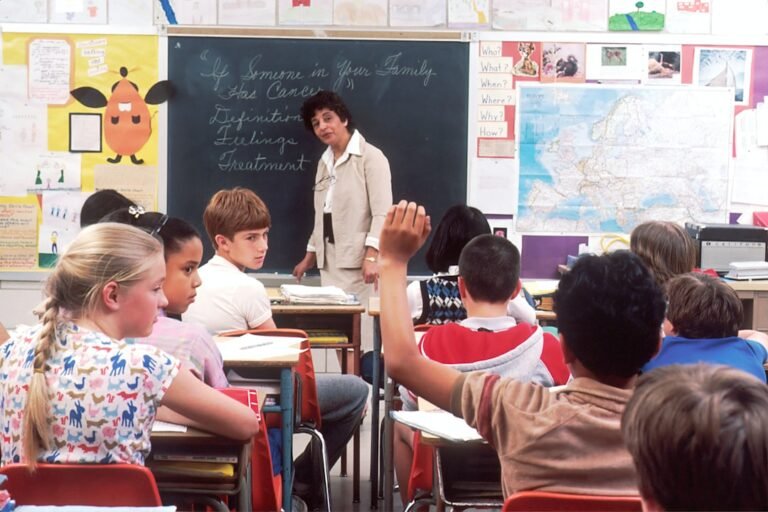 Happy teacher standing in front of her students in a classroom, celebrating Teachers' Day 2026