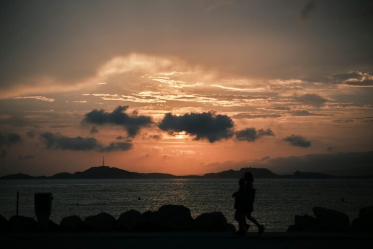 Couple walking together along the coast at sunset, symbolizing long-term romance