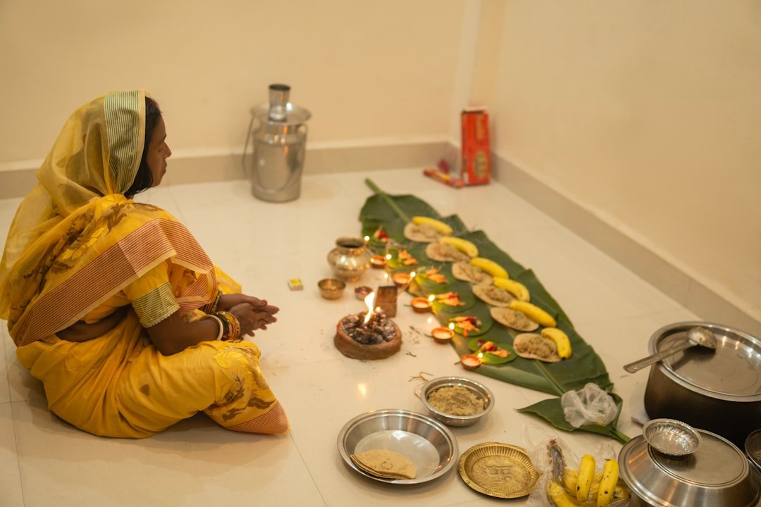 Woman in yellow sari performing a puja ritual with offerings